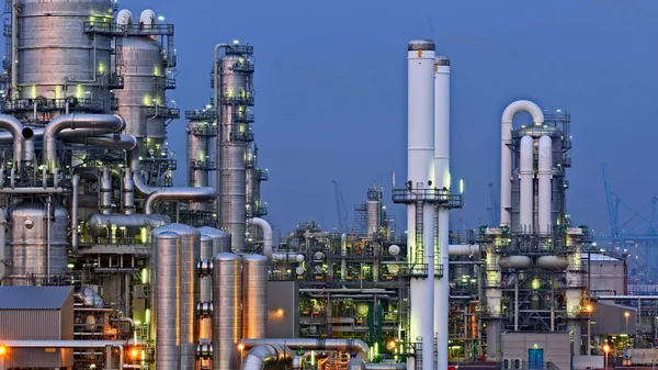 Petrochemical refinery complex at dusk with distillation columns and cooling towers, where activated carbon protects the plant process water at multiple points