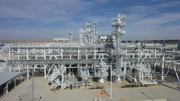 Middle East desert natural gas processing plant with distillation columns and piping, typical of the sour gas facilities at Ras Laffan, Shaybah, and Fadhili